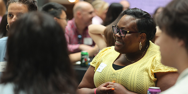 A young woman smiling and talking with a group at a tab